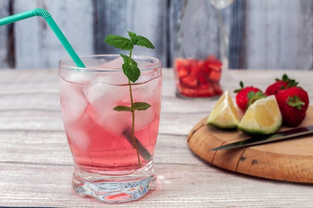 Un vaso de limonada rosa con hielo y una ramita de menta