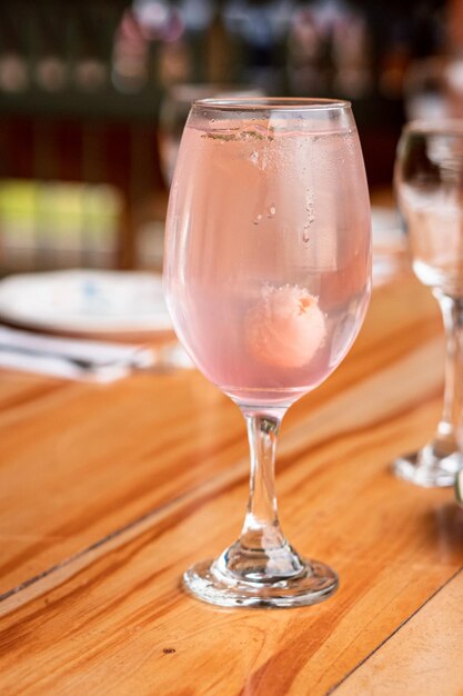 Foto un vaso de líquido rosa con cubitos de hielo se sienta sobre una mesa de madera.