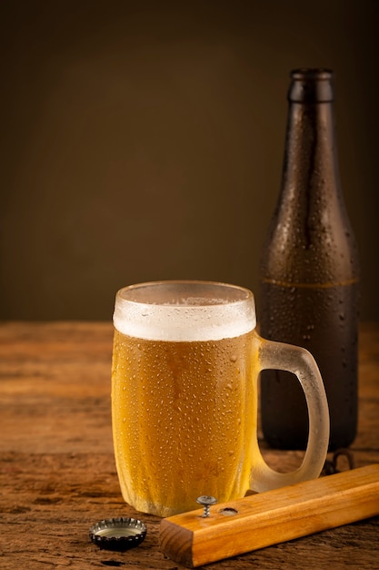 Vaso lleno de cerveza fría en la mesa de madera