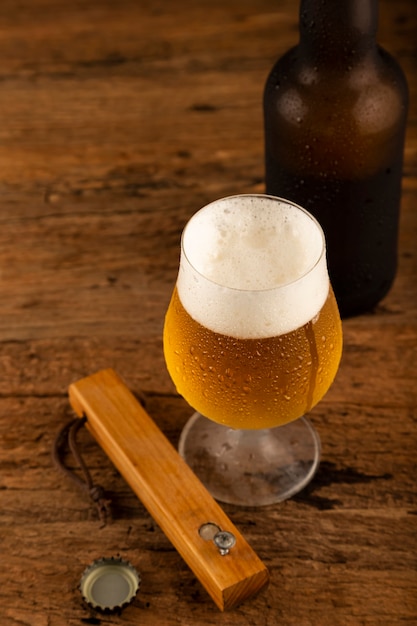 Vaso lleno de cerveza fría en la mesa de madera