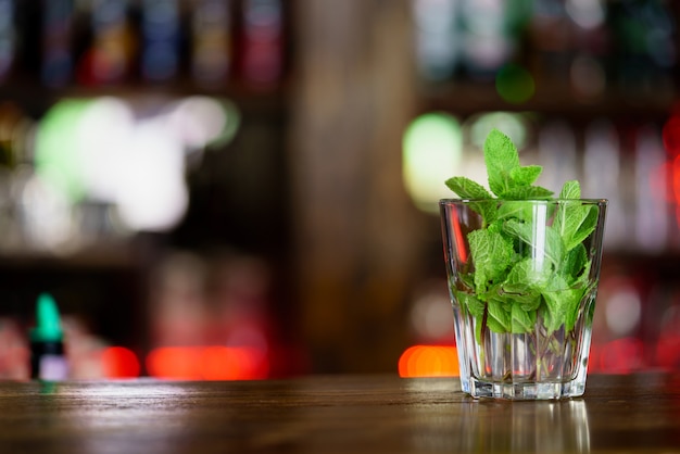 Un vaso con menta se encuentra en un estante de madera en el bar.