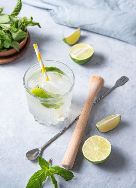 Vaso de mojito de limonada de lima sobre la mesa con cuchara de exprimidor de rodajas de lima y menta Imagen de la vista superior