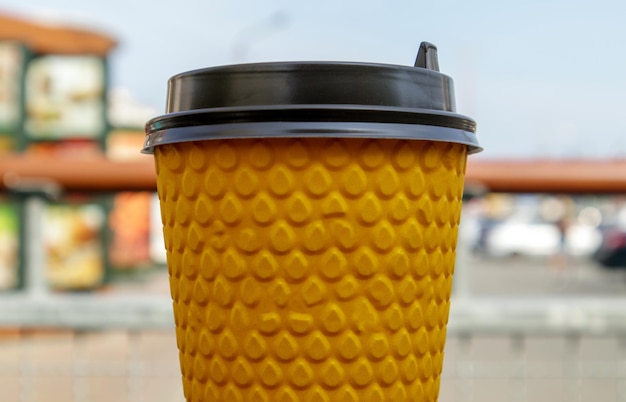 Un vaso de papel amarillo de té o café comida para llevar en una mesa en un café nadie un vaso desechable