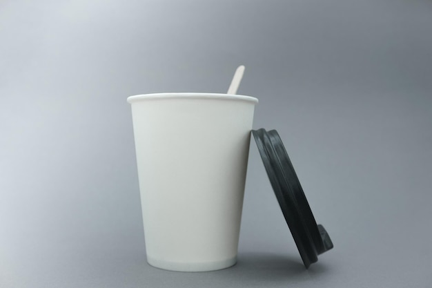 Foto vaso de papel blanco. lugar para el texto. un vaso de papel sobre un fondo gris.