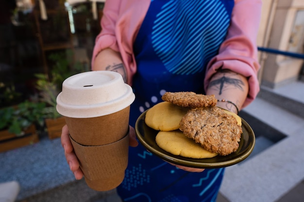 Foto un vaso de papel sin logo y galletas saludables sin gluten en manos de un camarero