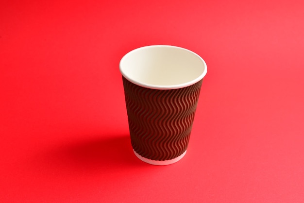 Vaso de papel marrón sobre un fondo rojo. Copie el espacio.