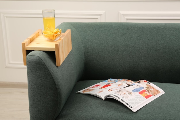 Vaso de patatas fritas de jugo y revista en el sofá con mesa de reposabrazos de madera en la habitación Elemento interior