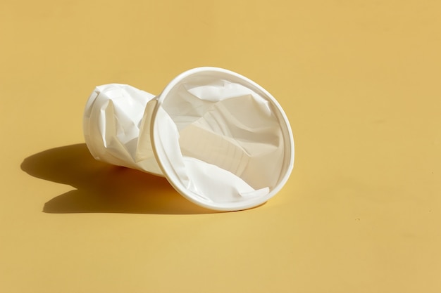 Vaso de plástico arrugado sobre un fondo uniforme. Concepto de contaminación ambiental.