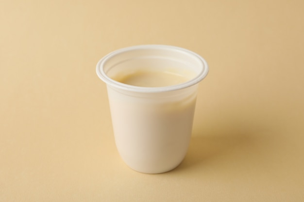 Vaso de plástico en blanco de yogur en beige