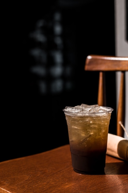 Vaso de plástico de café helado con refresco espumoso sobre la mesa