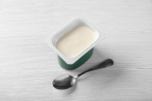 Vaso de plástico con delicioso yogur de vainilla sobre mesa de madera