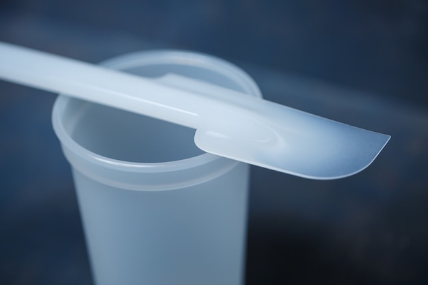 Vaso de plástico para mezclar crema sobre un fondo gris
