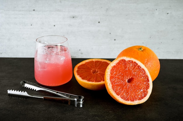 Un vaso de pomelo junto a una naranja cortada