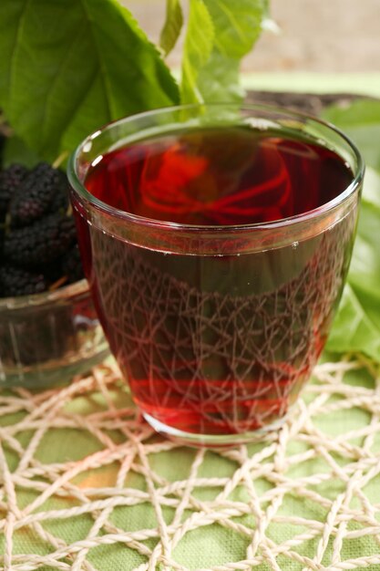 Un vaso de refrescante jugo de morera con bayas en la mesa de cerca