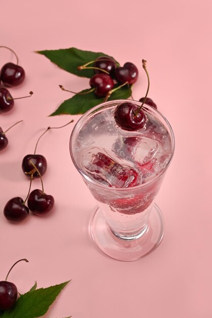 Vaso de refresco de cereza roja sobre fondo rosa