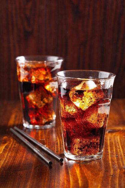 Vaso de refresco de cola fría con hielo sobre un fondo de madera