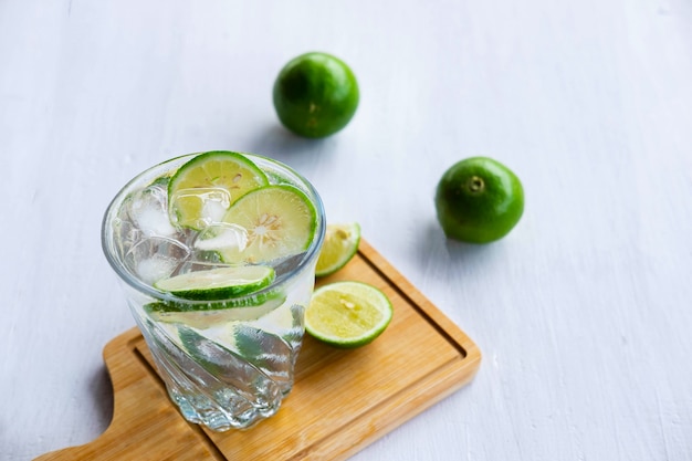 Un vaso de refresco, limón y lima sobre la mesa