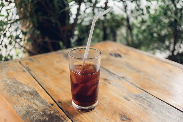 Vaso de refresco con una pajita blanca sobre la mesa.