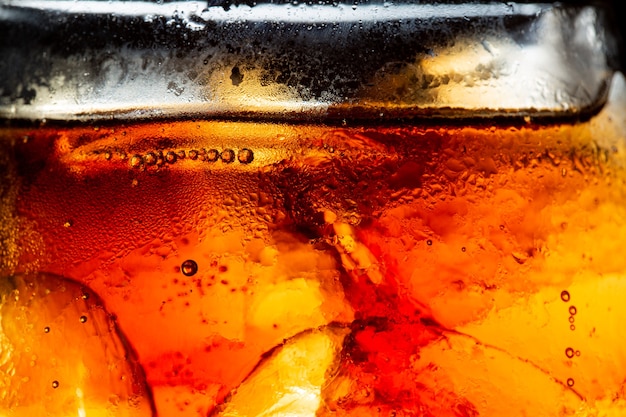 Vaso de refresco con salpicaduras de hielo sobre fondo oscuro Vaso de cola en concepto de fiesta de celebración