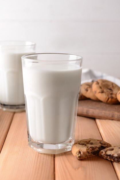 Vaso de sabrosa leche y galletas en la mesa de madera