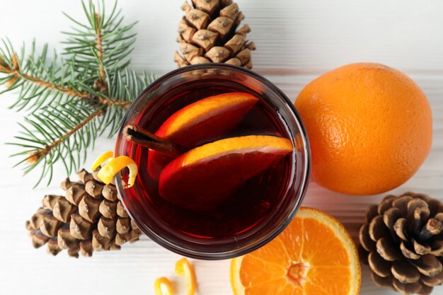 Vaso de sabroso vino caliente con naranja en la mesa de madera blanca, vista superior