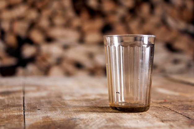 Un vaso sobre una mesa de madera y leña detrás.