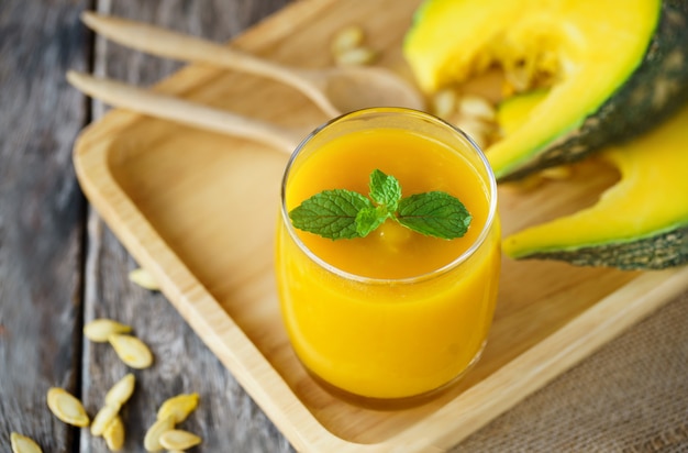 Foto vaso de sopa de calabaza en plato de madera ..