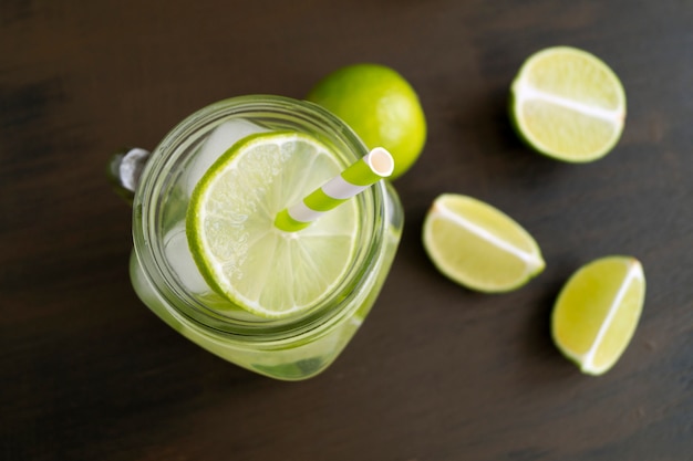 Vaso de tarro de masón de limonada con limón y paja sobre fondo-imagen de madera