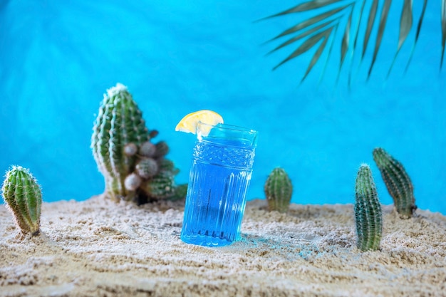 Un vaso de té azul tailandés en la arena con cactus