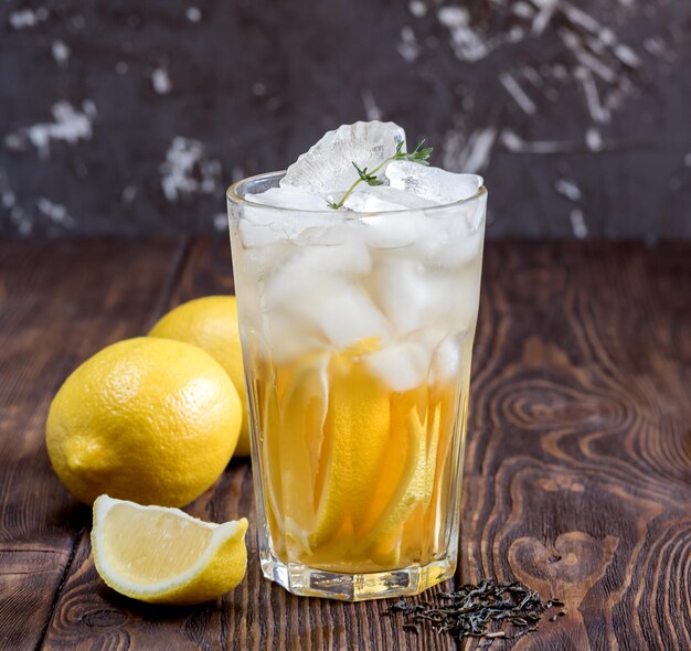 Vaso de té helado con limón sobre mesa de madera