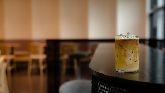 Un vaso de té helado se sienta en una mesa en un café.