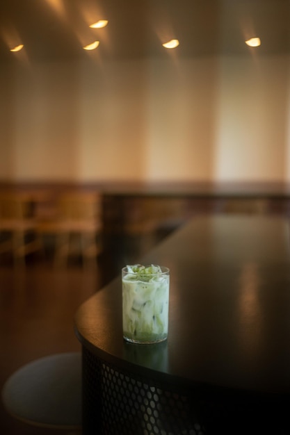 Un vaso de té helado se sienta en una mesa con una mesa de madera en el fondo.