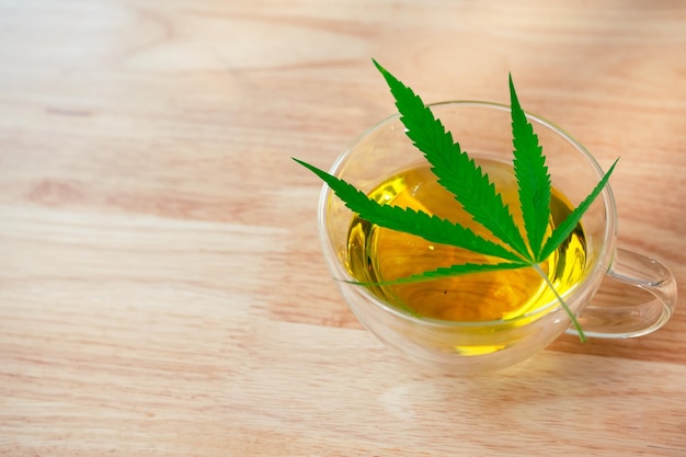 Un vaso de té de marihuana caliente en la mesa de madera Té de hierbas de cannabis con hoja verde