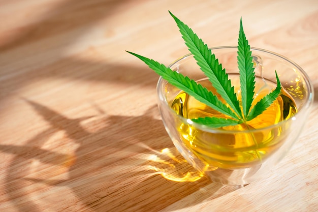 Un vaso de té de marihuana caliente en la mesa de madera Té de hierbas de cannabis con hoja verde