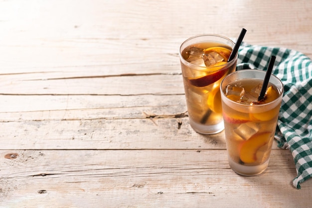 Vaso de té de melocotón con cubitos de hielo en la mesa de madera Espacio de copia