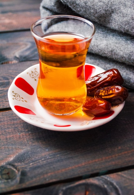 Foto un vaso de té negro y fechas en un plato