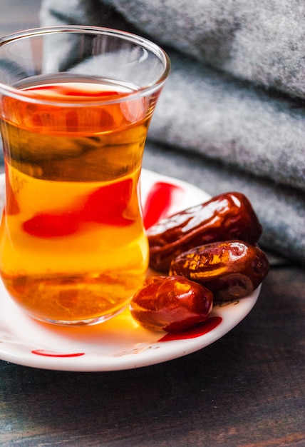 Un vaso de té negro y fechas en un plato