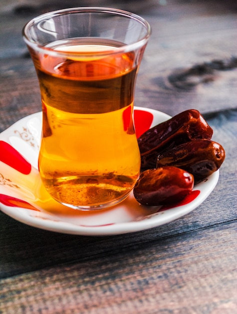 Un vaso de té negro y fechas en un plato