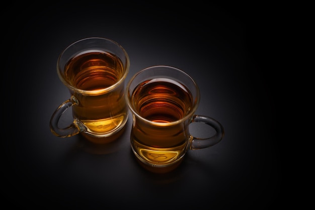 Un vaso de té turco sobre un fondo negro.