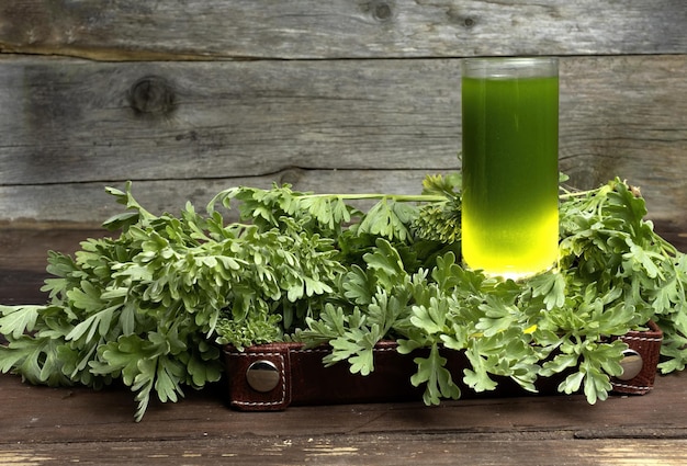 un vaso de té verde con una botella de líquido verde.