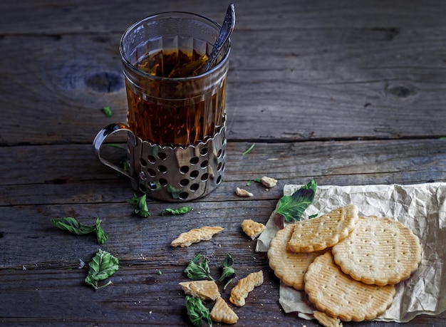 Un vaso de té con un viejo posavasos y galletas en la mesa