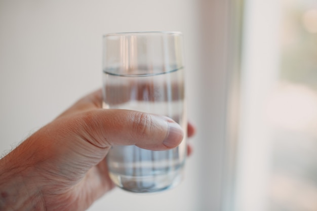 Vaso transparente con agua en mano.