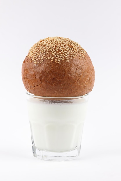 Vaso transparente completo de leche blanca con pan de centeno con semillas de sésamo aisladas sobre fondo blanco Útil desayuno closeup Concepto de comida saludable