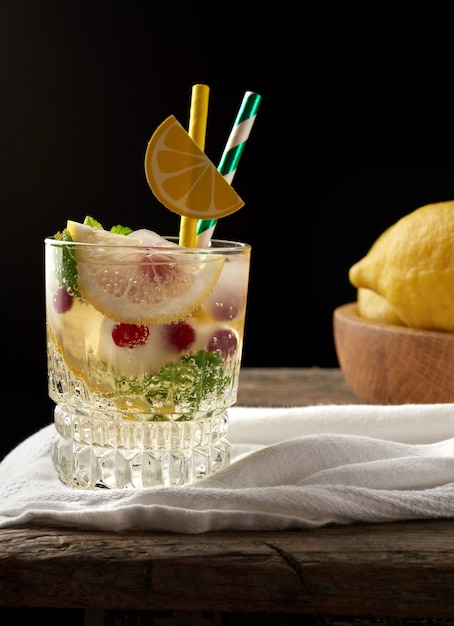 Vaso transparente con limonada y trozos de hielo, bayas rojas, una refrescante bebida de verano.