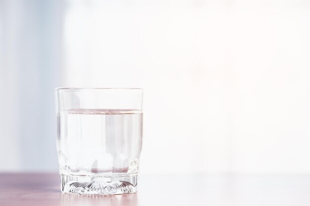 Foto un vaso transparente que contiene agua se coloca sobre una mesa de madera