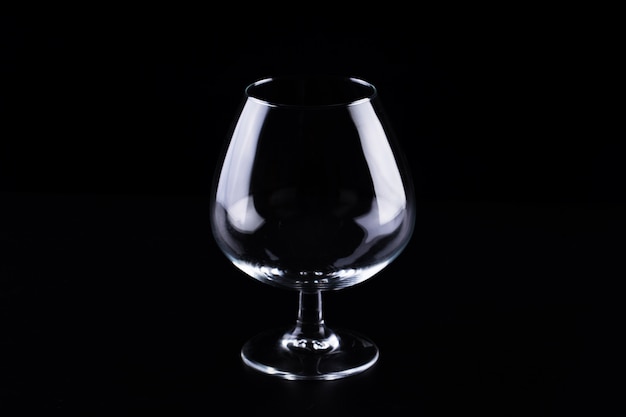 Foto vaso transparente vacío para coñac sobre un fondo negro