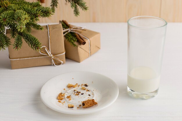 Vaso vacío de galletas de leche y migajas y un regalo debajo del árbol de Navidad