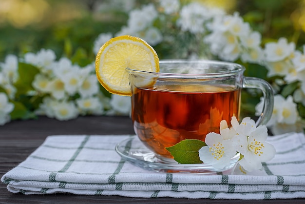 Vaso de vidrio con servilleta de té limón ramas de jazmín sobre una mesa de madera