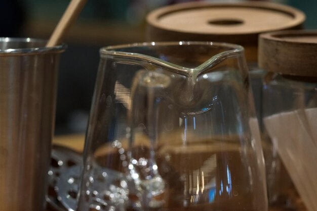 Un vaso de vidrio transparente sobre una mesa de madera con fondo borroso