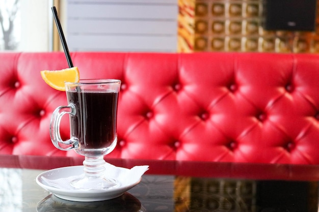 Un vaso de vidrio con vino caliente alcohólico fragante caliente sabroso marrón sobre una mesa en un café